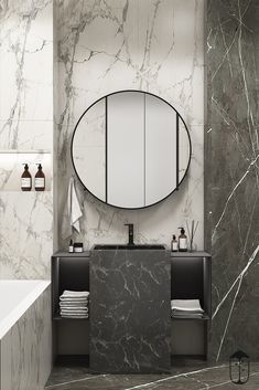 a bathroom with marble walls and flooring is shown in black and white, while a round mirror hangs on the wall