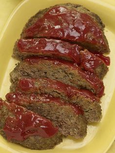 meatloaf with ketchup and mustard on a yellow platter text reads melt - in - your - mouth meat loaf