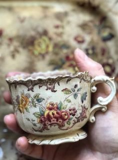 a person holding a cup in their hand with flowers painted on the inside of it