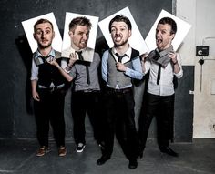 four men standing in front of a wall with pictures on their faces and ties around their necks