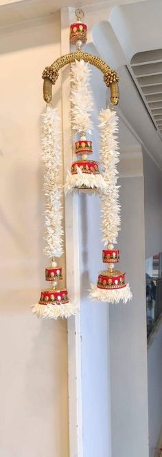 a tall white pole with three red and gold bells hanging from it's sides