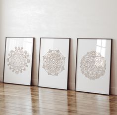 three framed art prints on the wall in an empty room with hard wood flooring