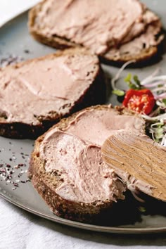 a plate that has some bread and meat on it, with salad in the background