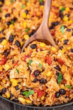 mexican rice and black beans in a skillet with a wooden spoon on the side