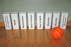 a basketball sitting next to five trash cans with labels on them and an orange ball in the middle