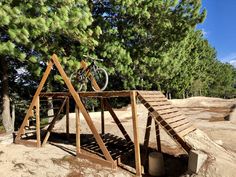 a bicycle is parked on top of a wooden structure in the sand near some trees