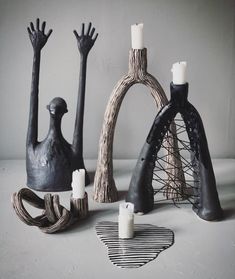 three black and white ceramic sculptures with candles