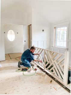 a man is painting the inside of a room with white walls and wood flooring