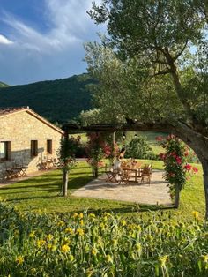 an outdoor dining area in front of a stone building with flowers growing on the lawn