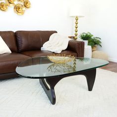 a living room with a brown leather couch and glass coffee table in front of it