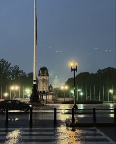 a city street at night with cars driving on the road and an obelisk in the background