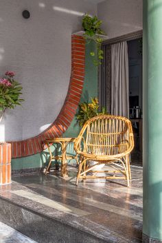 a wooden chair sitting on top of a tiled floor next to a planter filled with flowers