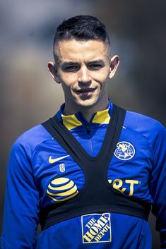 a soccer player is wearing a blue and black uniform with yellow details on his chest