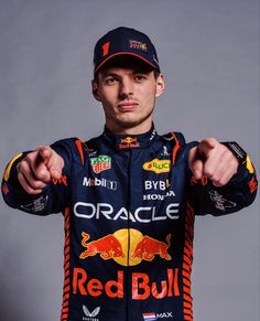 a man in a red bull racing suit pointing at the camera with his fist out