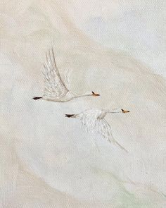 two white birds are flying in the sky