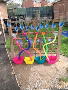 several plastic bowls and spoons are lined up on the ground in front of a fence