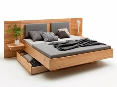 a bed with two drawers underneath it and a plant in the bottom right hand corner