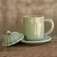 a green cup and saucer sitting on top of a wooden table