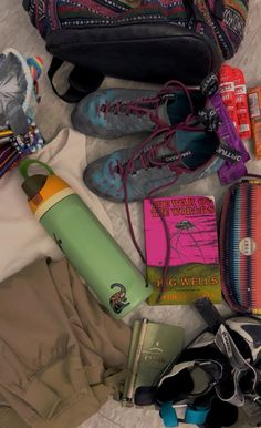 the contents of a purse and shoes are laid out on top of a bed sheet