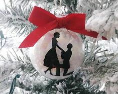 a christmas ornament with a silhouette of a man holding a woman's hand