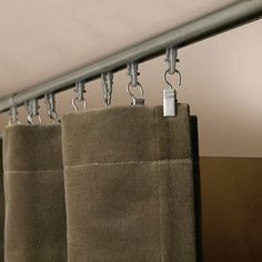 two towels hanging on a rail in a room with brown walls and curtains behind them