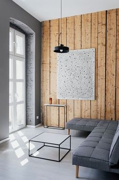 a living room with wood paneling and grey couches