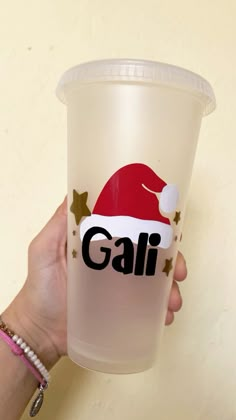 a person holding up a plastic cup with the word gali on it and santa's hat