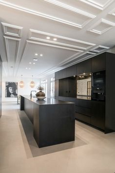 a large kitchen with black cabinets and white ceilinging, along with an island in the middle