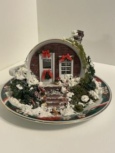 a plate with a house on it and christmas decorations in the front window, sitting on a table