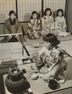 an old black and white photo of some women sitting on the floor with tea cups