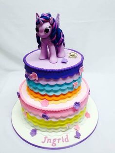 there is a cake that looks like a pony on top of the rainbow tiers