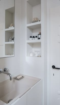 a bathroom with white walls and shelving above the sink