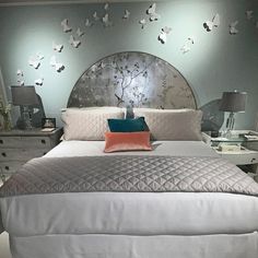 a large bed with white sheets and pillows in a room that has butterflies on the wall