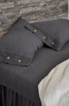 a bed with two pillows on top of it next to a wooden headboard and wall