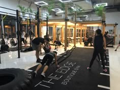 a group of people in a gym doing exercises on exercise mats with large tire tires