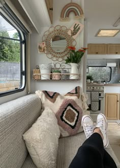 a person's feet resting on a couch in front of a window with a mirror above it