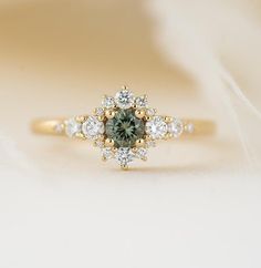 a green and white diamond ring sitting on top of a beige surface with other diamonds