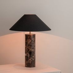 a table lamp sitting on top of a white table next to a black lampshade