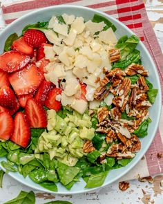 a salad with spinach, strawberries and pecans in it on a plate