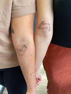 two people holding hands with tattoos on their arms