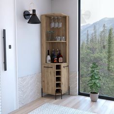 a wooden cabinet filled with bottles and glasses next to a window overlooking the forest in front of it