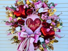 a heart shaped wreath with flowers and hearts attached to the front door is adorned with ribbons