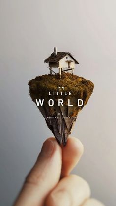 a hand holding a tiny house on top of a piece of land with the words, my little world