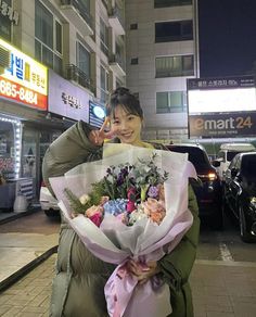 a woman is holding flowers on the street