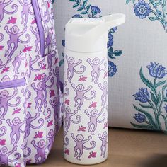 a purple and white monkey print backpack next to a water bottle