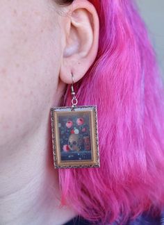 These fine art earrings depict a still life painting of a skull and vibrant florals with an ornate gold frame by Jan Van Kessel the Elder in 1670.  These unique drop earrings are the perfect gift for a witch, art lover, Halloween lover, painter, or history buff in your life. Wear them to a party, class, or to a museum! (Or anywhere else for that matter) These earrings are made of acrylic, an epoxy layer, and hypoallergenic nickel-free stainless steel earring hooks.  You will receive:  1 pair of Dark Academia Earrings, Academia Earrings, Artist Earrings, Vanitas Still Life, Painting Earrings, Unique Drop Earrings, Frame Earrings, Skull And Flowers, Artistic Earrings