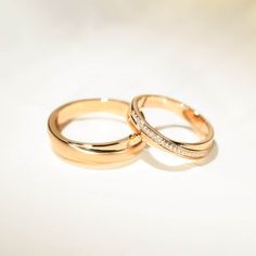 two gold wedding rings with diamonds on them sitting side by side against a white background