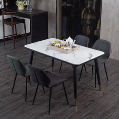 a dining table with four chairs and a tray of food on it in front of a kitchen