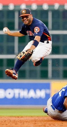 a baseball player sliding into home plate to catch the ball while another player is on the ground behind him