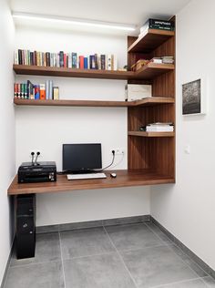 a desk with a computer on top of it next to a book shelf filled with books